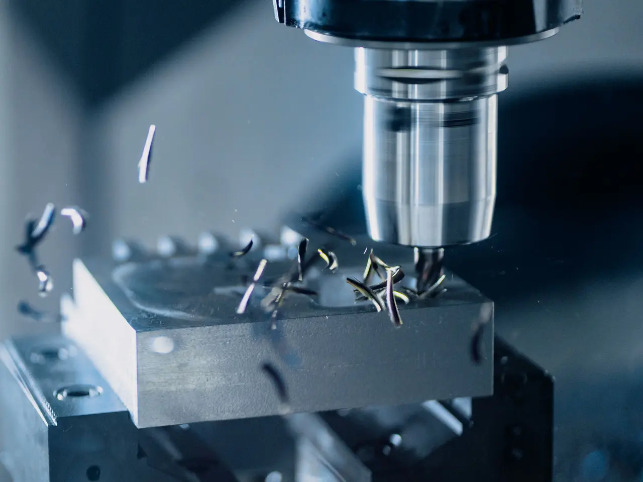 CNC freze takımı metal bloğu işlerken talaşlar havaya saçılıyor
